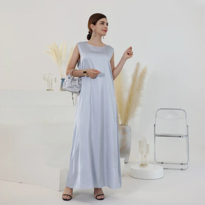 Woman in white Ramadan inner dress standing in minimalist room with pampas grass and decor.