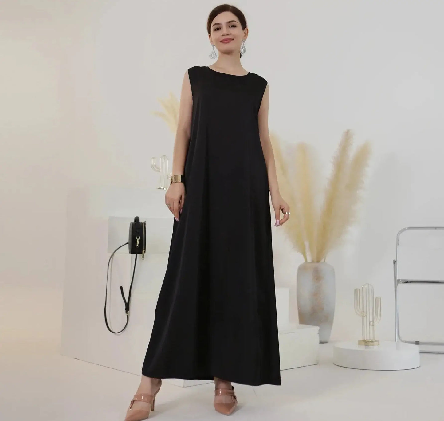 Woman wearing a black inner abaya dress, standing gracefully in a modern, minimalistic setting.