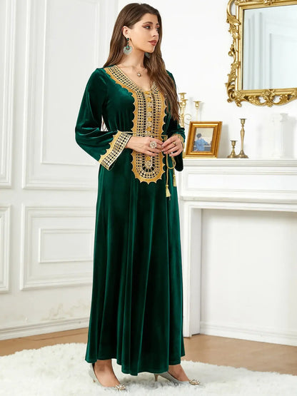 Woman wearing Morocco Party Dress in green velvet with gold lace-up detailing, standing in elegant room with ornate mirror and decorations